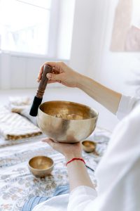 A person gently playing a Tibetan singing bowl indoors, promoting relaxation and mindfulness.